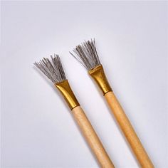 two wooden and metal brushes on a white surface