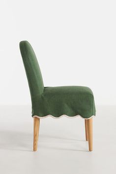 a green chair sitting on top of a white floor next to a wooden legrest