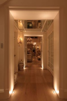 the hallway is lit up with lights and wood flooring, along with white walls