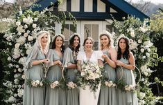 a group of women standing next to each other in front of a flower covered building