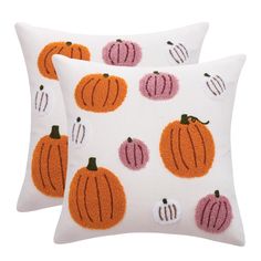 two white pillows with orange and pink pumpkins on them