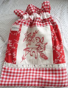 a red and white checkered drawstring bag sitting on top of a bed