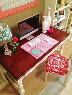 a desk with a computer, lamp and flowers on it in a home office area