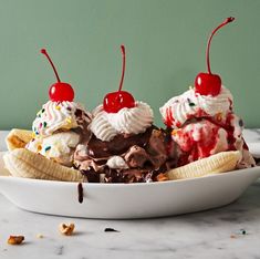 three ice cream sundaes with cherries and bananas in a bowl on a table