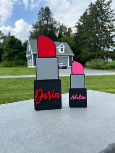 two lipstick shades sitting on top of a cement table in front of a green field