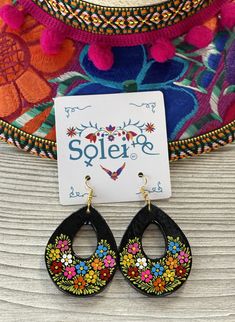 a pair of black earrings with colorful flowers on them