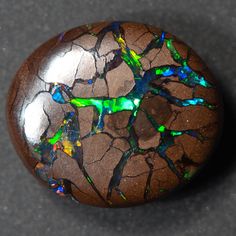 a rock that has some kind of colorful substance on it's surface and is sitting on the ground