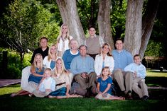 a large family poses for a photo in front of some trees