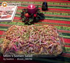 a casserole dish with red onions and shredded carrots on a table next to a candle