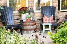 two adiron chairs sitting on top of a patio next to a barrel filled with flowers