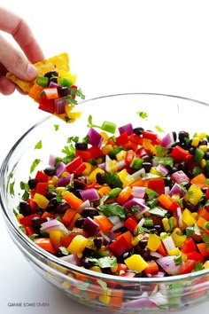 a glass bowl filled with lots of different colored vegetables and garnished with cilantro