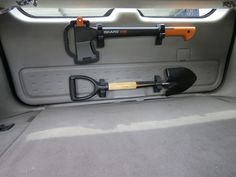 an orange and black shovel sitting in the back of a car with its door open