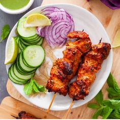 grilled chicken skewers with cucumbers and onions on a white plate