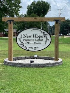 the sign for new hope primitive baptist church in front of a grassy field with trees