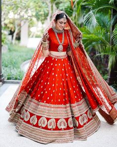 a woman in a red and gold bridal gown with her hands on her hips