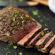 a piece of steak on a cutting board with parsley sprinkled on top