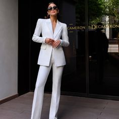 a woman wearing a white suit and sunglasses