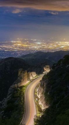 a winding road in the middle of a mountain at night with lights shining on it