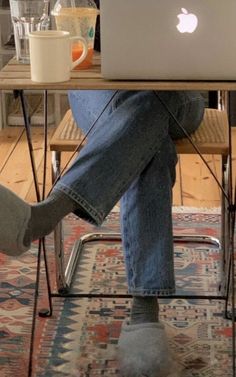 a person sitting at a table with an apple laptop on their lap and feet in the air