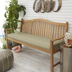 a wooden bench sitting on top of a hard wood floor next to potted plants