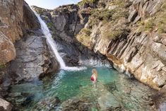 a person standing in the water next to a waterfall