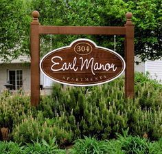 the entrance sign to an apartment complex with trees in the background and bushes around it