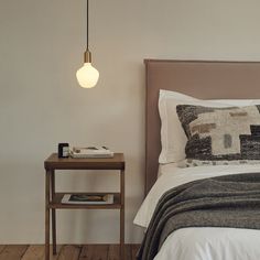 a bed sitting next to a night stand with a lamp on it's side