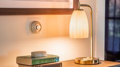 a lamp on a table next to some books and a framed picture in the background