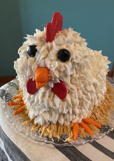 a cake made to look like a chicken sitting on top of a tablecloth covered table