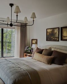 a bedroom with a bed, lamps and pictures on the wall