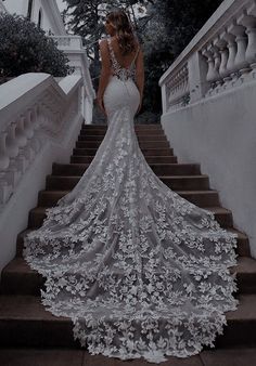 a woman in a wedding dress standing on some stairs with her back to the camera