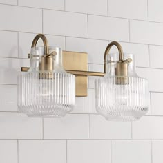 two light bathroom fixture with clear glass shades on the front and back of the lights