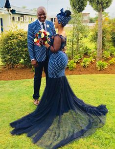 a man and woman dressed in blue standing on the grass with their arms around each other