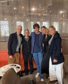 a group of people standing next to each other in front of a table with food on it