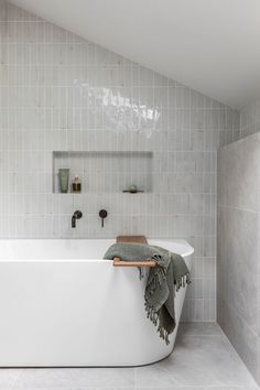 a white bath tub sitting in a bathroom next to a wooden shelf with towels on it