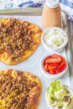 two homemade pizzas on a tray with salad and dressing