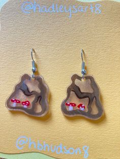 the earrings are made out of clay and have red mushrooms on them, with words underneath