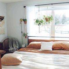 Absorb inspiration from a boho bedroom with sheer drapes that cover a large window. A rattan chair is tucked in the corner beside a bed covered in tan and white bedding. Hang small plants around the room to fully embrace the boho style...   Image: mainemadehome