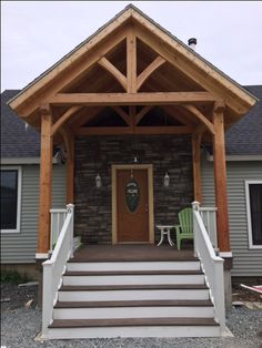 a porch with steps leading to the front door and two green chairs on either side