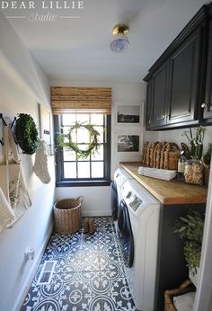 a laundry room with black cabinets and tile flooring is shown in this image from dear lillie studio