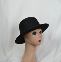 This black wool felt hat has a flat 2 1/2-inch brim and rounded crown. The small/medium will fit 21 to 22 1/2-inch head size, (there is a sizing cord inside the band to adjust to your head size), the large will fit up to 23 1/4 inch head size and the XLG will fit up to 24 1/8 inch head size. This hat is made in a classic vintage Annie Hall style hat and is suitable for any fall and winter weather. Classic Black Hat With Flat Crown, Adjustable Fur Felt Cloche Hat With Flat Brim, Adjustable Wool Cloche Hat With Flat Brim, Classic Black Hat Band With Flat Crown, Winter Derby Felt Hat With Flat Brim, Adjustable Wool Top Hat With Flat Brim, Classic Black Fedora With Flat Crown, Black Wool Felt Hat With Flat Crown, Curved Brim Felt Hat For Derby And Winter