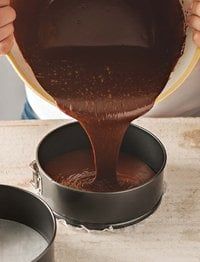 a person pouring chocolate into two pans