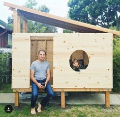 a man sitting in a small wooden structure with a woman looking out from inside it