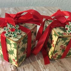 two small boxes with bows on them sitting on a wooden table next to each other