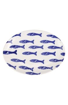 a blue and white platter with fish on the side, in front of a white background