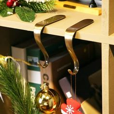 two christmas ornaments hanging from hooks on a shelf next to a bookcase with books