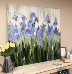 a painting is displayed on a shelf with flowers