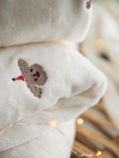 a teddy bear is embroidered onto the back of a white blanket with lights in the background