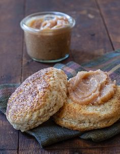 two biscuits with peanut butter sitting on a napkin next to a jar of peanut butter