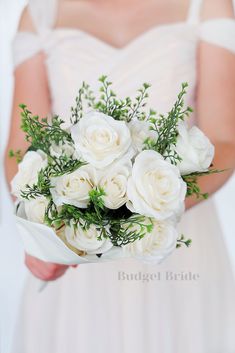 a bride holding a bouquet of white roses